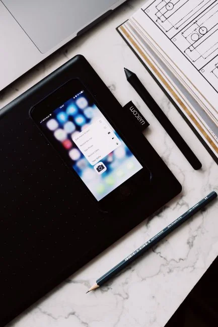 Vue rapprochée d’un smartphone affichant une image floue, posé sur un bureau à côté d’un ordinateur portable.